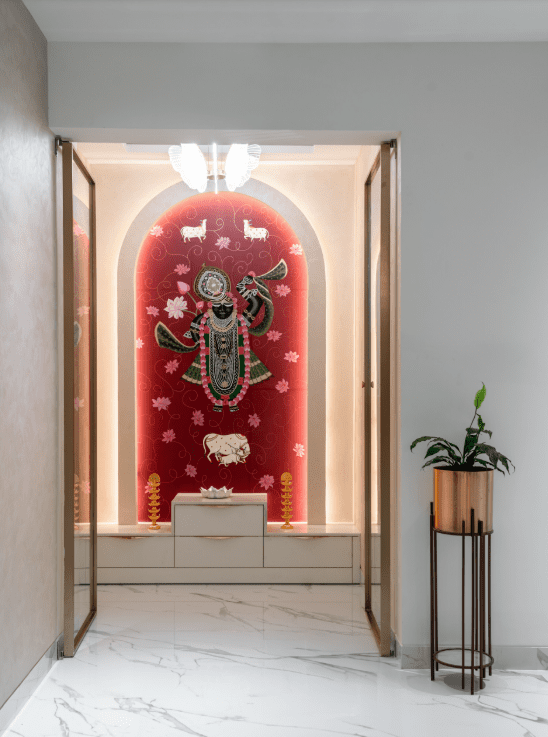 Pooja room design with arched glass doors and backlit red panel in Pune