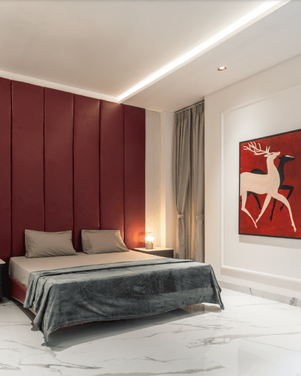 Bedroom design with maroon channel-tufted wall and deer wall art in Pune