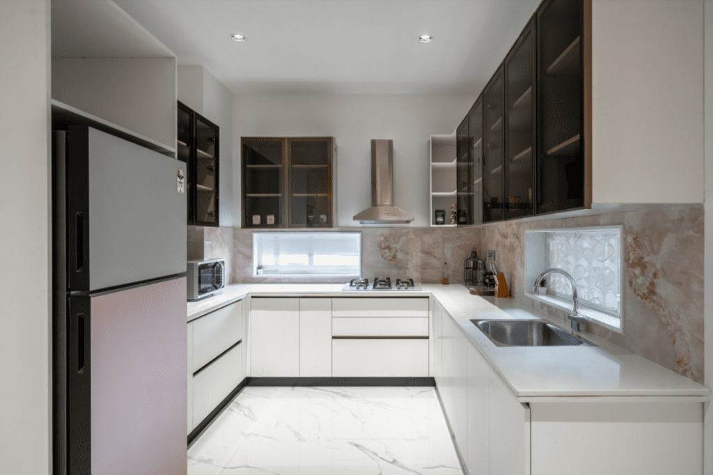 Modular kitchen design with white cabinets and marble backsplash in Pune
