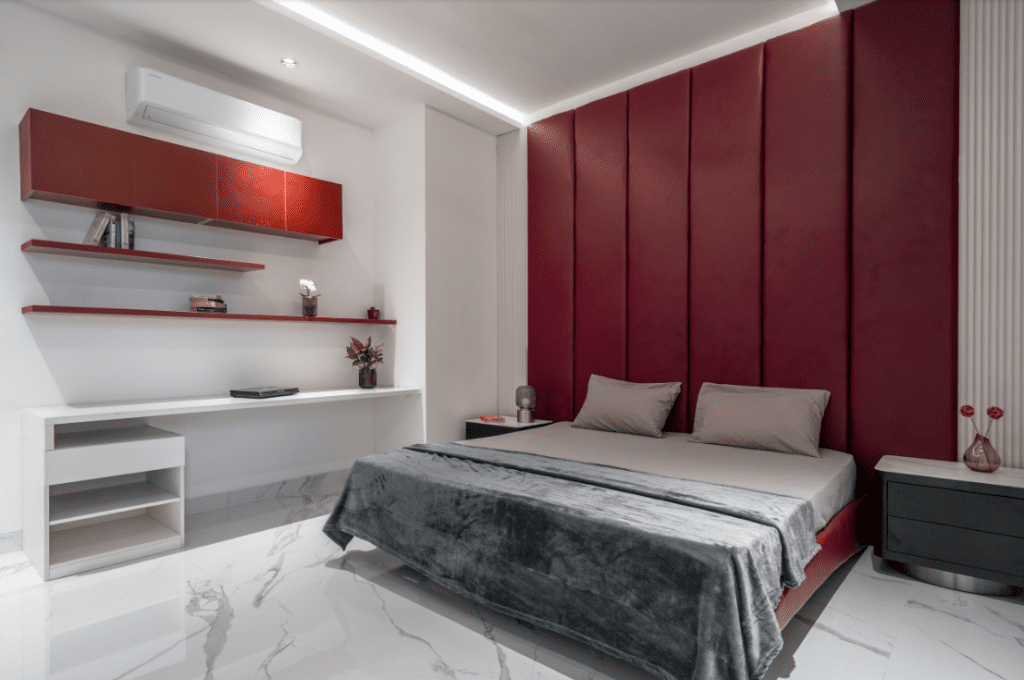 Bedroom design with maroon tufted headboard wall and grey bedding in Pune