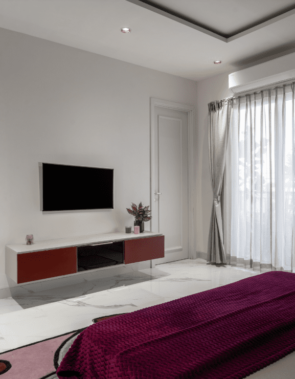 Bedroom design with floating TV unit and maroon accents in Pune