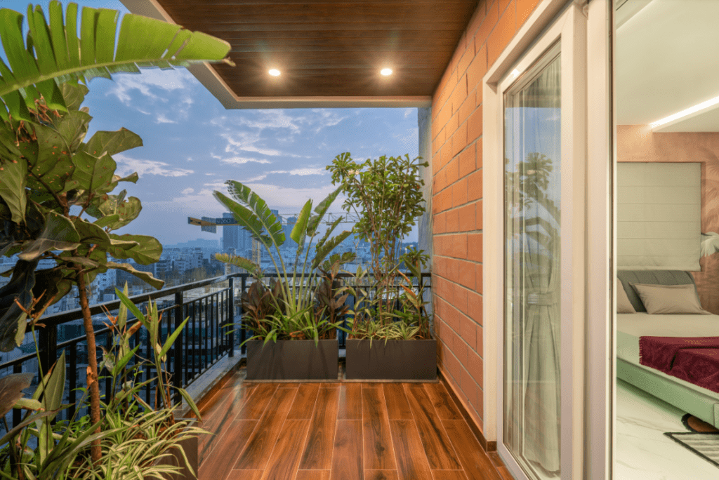 Balcony garden design with wooden flooring, exposed brick wall, and city view in Pune